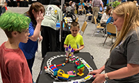  Students listening to a teacher explain the robotics display on a table.